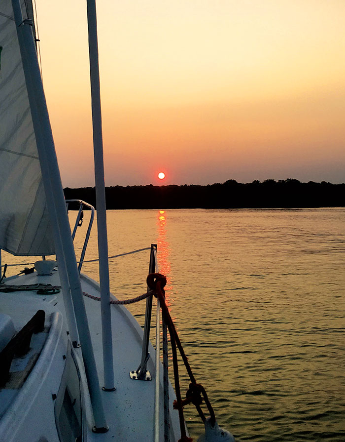 Bow of a sailboat pointing towards sunset