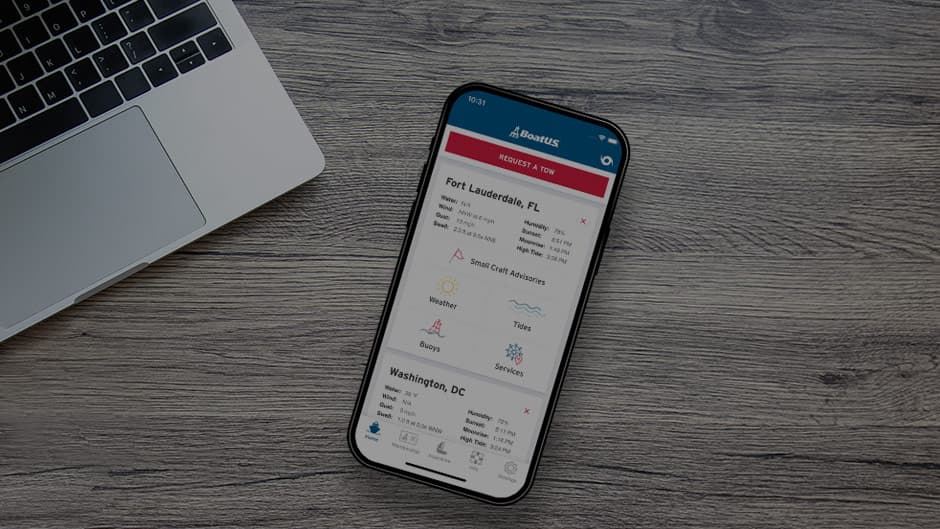 a phone with the boatus mobile app on a table alongside a laptop